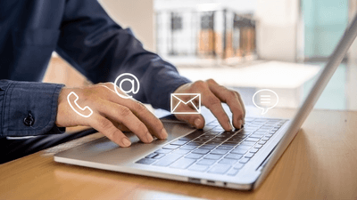 Person clicking on laptop with email and phone icons hovering around