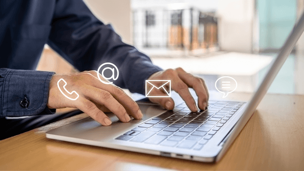 Person clicking on laptop with email and phone icons hovering around